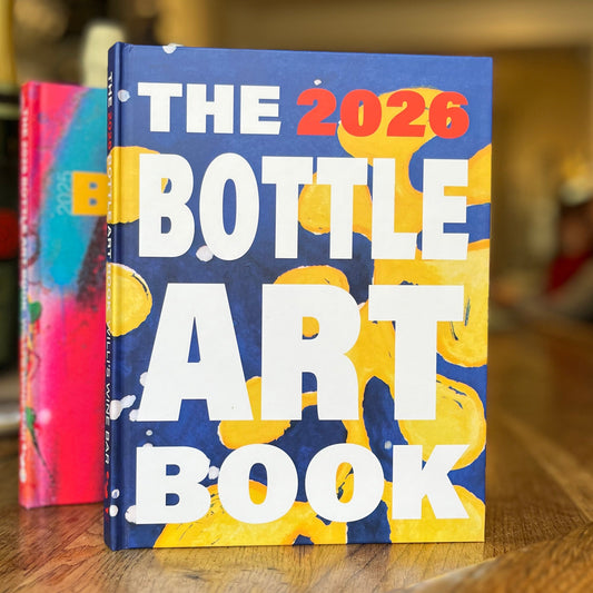 Book titled 'The 2026 Bottle Art Book' with colorful design on a wooden surface.